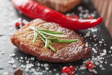 grilled steak with rosemary and chili pepper on dark stone