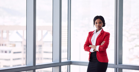 formally dressed african business woman looking into the camera with her arms crossed while...