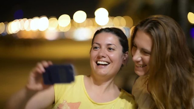 Young women taking selfie, city lights in the background