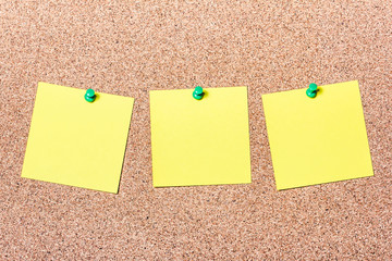 Three yellow notes pined in a row to cork board. Empty reminder cards.