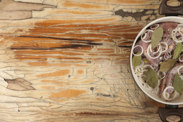 raw rabbit on a wooden Board with ingredients for stewing onion, pepper, bay leaf, rosemary and knife on a wooden background - top view