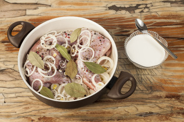 raw rabbit on a wooden Board with ingredients for stewing onion, pepper, bay leaf, rosemary and knife on a wooden background - top view