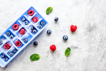 blueberry and raspberry in ice tray on stone background top view mock-up