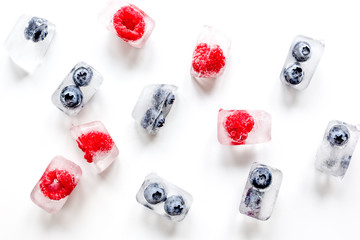 Frozen berry in ice cubes on white background top view
