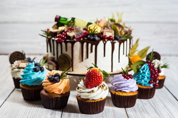 Chocolate cupcakes and cake. Cupcakes with berries,fruit,strawberries.colorful cupcake,tasty cake,colorful cream,candies, wooden background,close up,dessert concept,Birthday cake with wine,rome