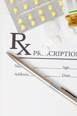 Different pills and silver color pen over medical prescription form