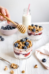 Morning granola with yogurt and berries on white kitchen background