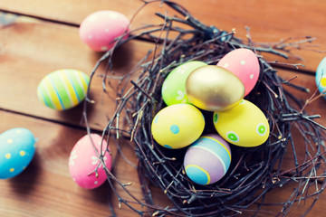 Fototapeta na wymiar close up of colored easter eggs in nest on wood