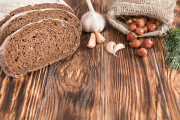Bread, garlic, fennel, filbert on old wooden table.