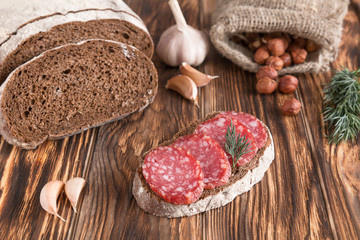 sandwich with salami. Bread, garlic, fennel, filbert on old wooden table.