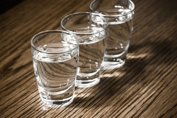 Vodka shots filled with alcohol on wooden bar.