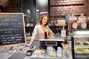 happy woman or barmaid at cafe counter