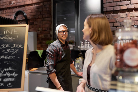 happy bartenders at cafe or coffee shop counter