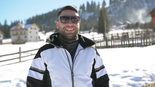 Good-looking Man Wearing Eyeglasses is Enjoying Vacation in the Mountains During Winter Time. Closeup Outdoors Portrait of Smiling Skier on Countryside Background.