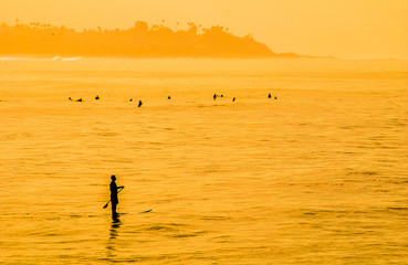 SUP surfer paddles on ocean off California beach