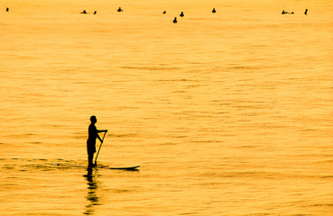 Sunset Silhouette of a man on Paddle Board SUP off Southern California beach	