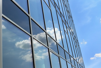 Fototapeta na wymiar Clouds reflected in windows of office building