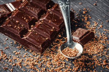 Close up of dark chocolate and spoon on dark wooden background