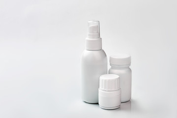 White containers with medicine. Small spray bottle.
