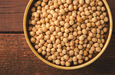 Chick-pea in bowl on wooden background. Horizontal, toned