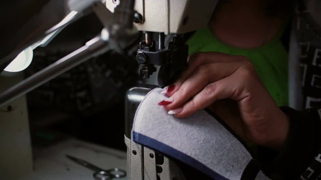 Close-up of woman s hand making stitch on the sewing machine. Worker sews leather for shoe production. 4K
