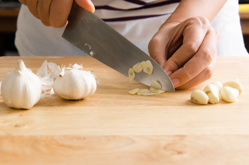 Woman chopping garlic on wooden board for cooking