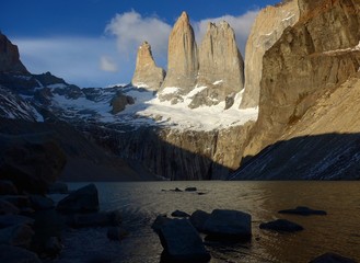 Granite pillars tower above a lake at sunrise in the Torres Del Paine National Park, Patagonia.