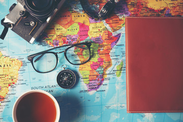 Time to go travel concept : Top view of eye glasses with compass and camera on world map background.