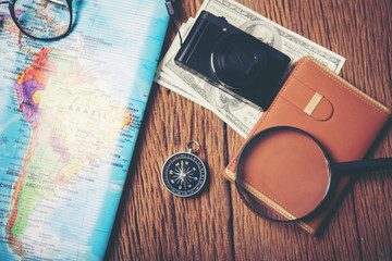 Close up of camera,notebook,eyeglasses,money and world map on wooden table. Prepare for holiday. Travel concept.