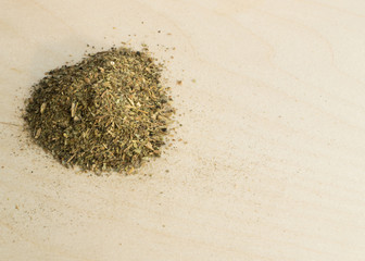 Heap of Dried Basil Flakes on Wood Background