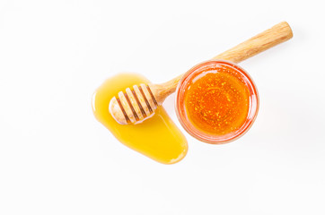 Honey dripping with honey stick and honey in glass.