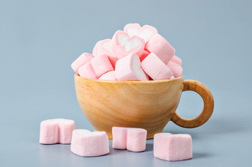 Heart shape pink marshmallows in wooden cup.