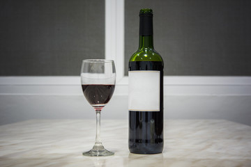 A bottle of red wine and a glass on table