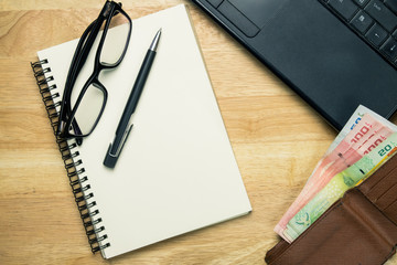 Notebook or note pad,smart phone,cup of coffee and glasses on Brown wooden background top view with copy space. office desk concept