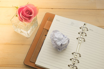 pink rose with diary on wooden desk