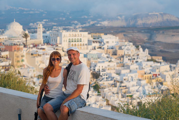 Fototapeta na wymiar Couple on island of Santorini. Cheerful couple travels to islands of Greece, the most romantic island -Santorini. concept of family tourism and travel, Man and woman on the background of sunset city 