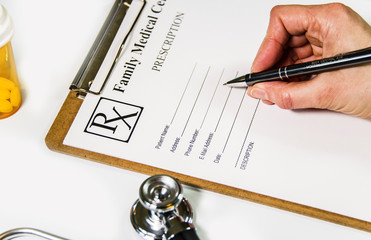 Doctor woman writing a prescriptions on Rx form in the consulting office