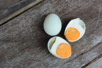 Salted egg cut by half exposing its yolk inside on a wooden background