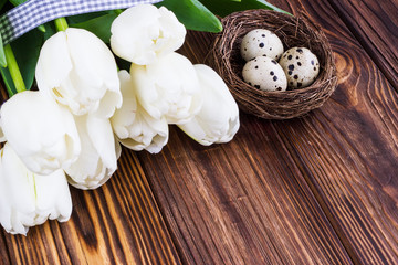 Bouquet white  tulip flowers with easter eggs on old wooden table. Place for text.