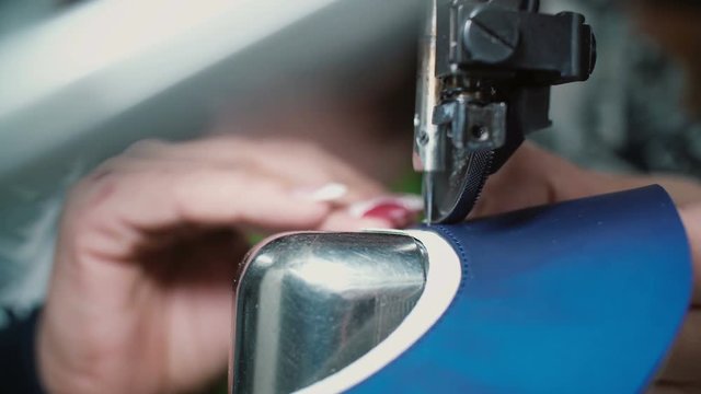 Close-up view of woman s hands working at the garment factory using the sewing machine to join several pieces. 4K