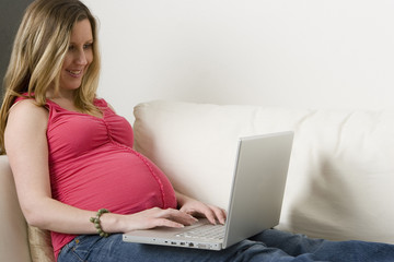 Pregnant woman typing on the computer.