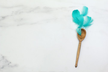 Composition of turquoise feathers and spoons. Marble surface.  Flat lay, top view