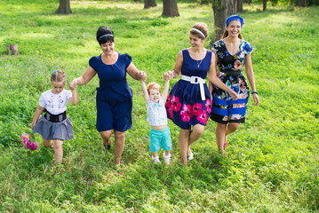 Fototapeta premium Big happy family on a walk in the park. Grandmother, daughter and granddaughter walk in the spring. Women of all ages have fun together 
