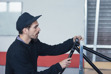 Side view of man constructing bicycle