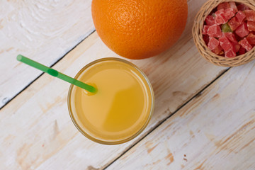 A whole orange with a glass of orange juice on a white wooden background. View from above.