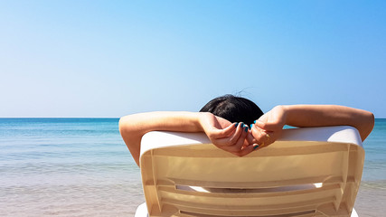 Woman lay on the white armchair on the beach