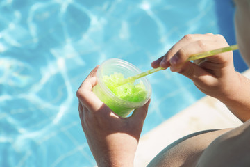 Boy drinks ice from juice at the pool