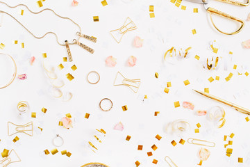 Beauty blog background. Gold style feminine accessories pattern. Golden tinsel, scissors, pen, rings, necklace, bracelet on white background. Flat lay, top view.