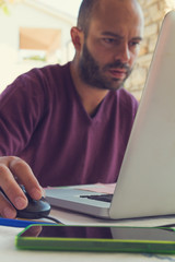 Man working on his laptop. Focus is on the hand and mouse.