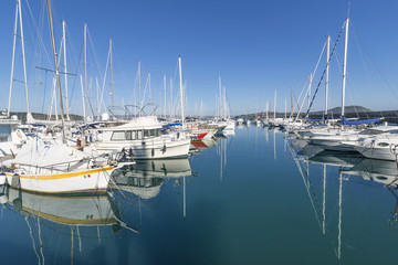 Fototapeta na wymiar Wonderful mirror reflections of boats moored in the waters of the tourist port of Talamone, Grosseto, Tuscany, Italy